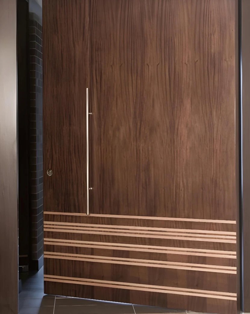 Tall walnut pivot door with a stainless pull and light inlay stripes